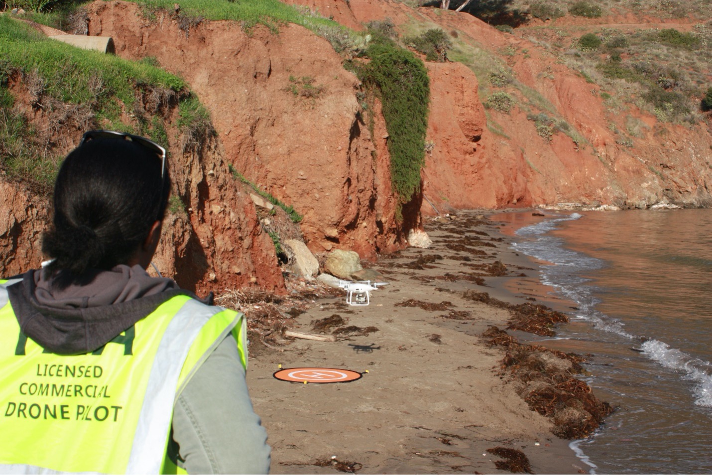 Wrigley Graduate Fellow Charnelle Wickliff lands a drone on a stretch of sand near the water