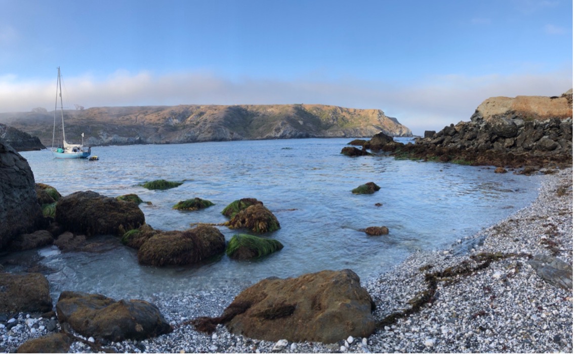 an early morning view of Catalina Island's Little Harbor, a small harbor surrounded by rocky shores with a small boat anchored in the background