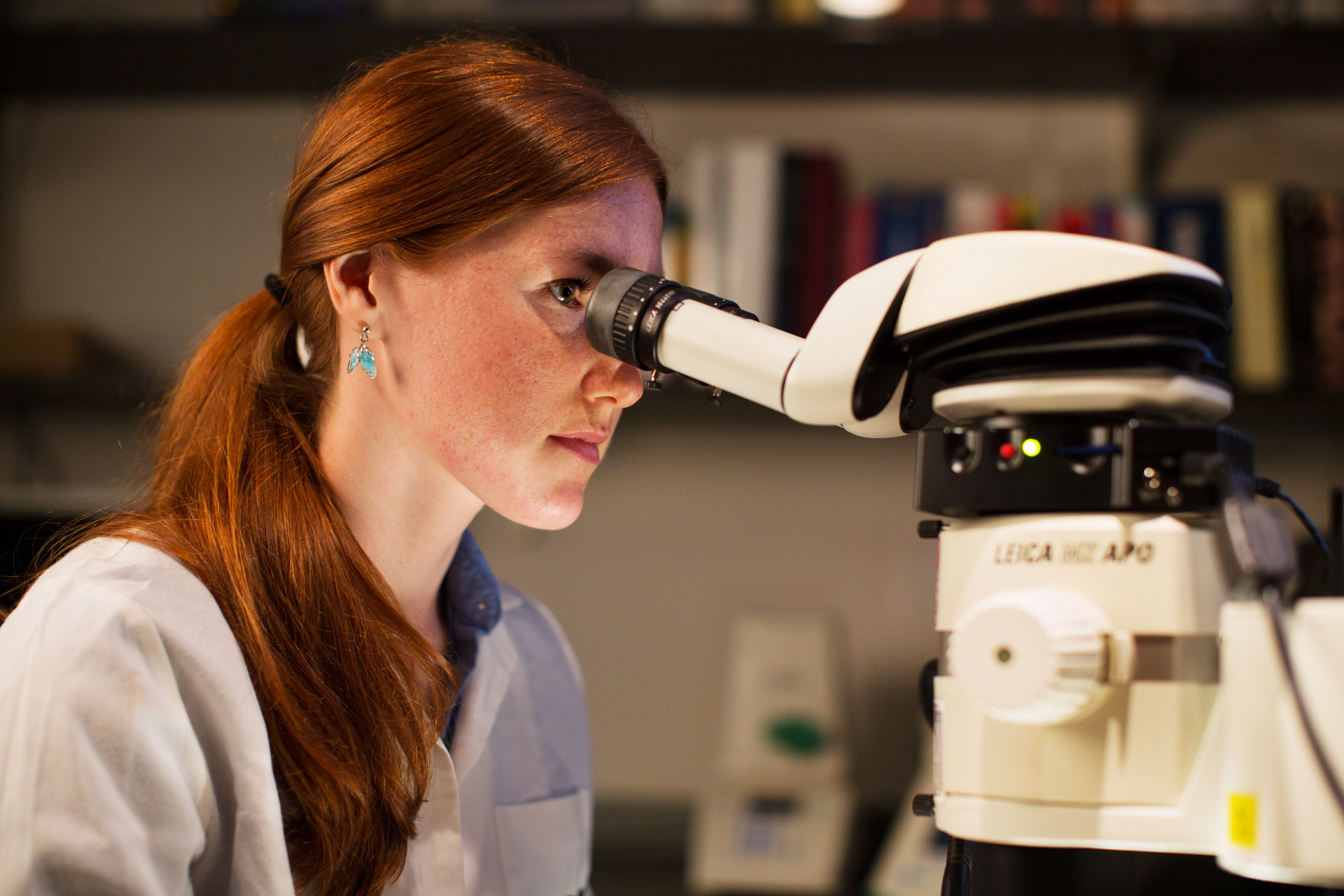 Student in a dark lab looking through a microscope