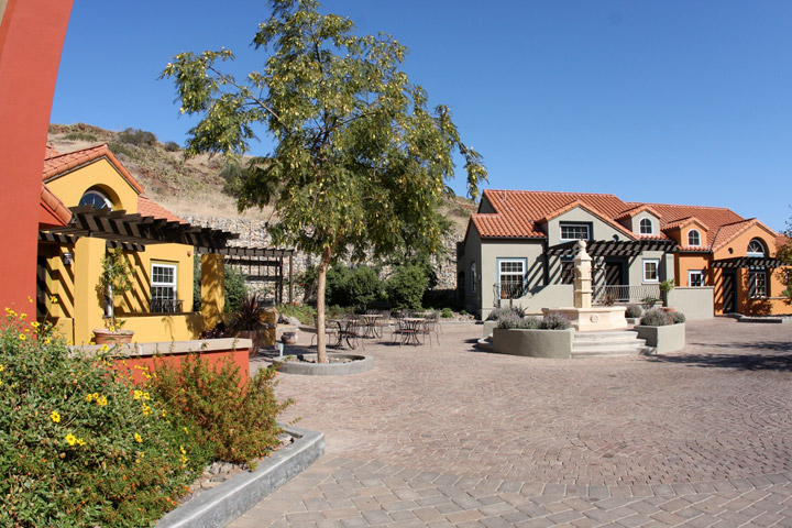 Gold, gray, and brick-red stucco houses surround a fountain in a cobblestone courtyard at the Boone Center on the Wrigley Marine Science Center campus