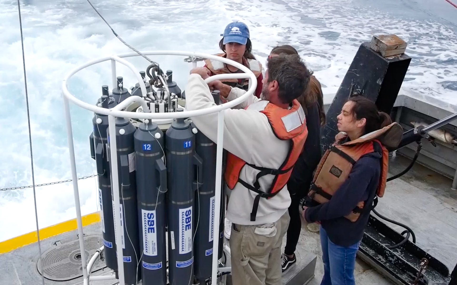 SPOT participants on a boat deploy the CTD rosette for water sampling