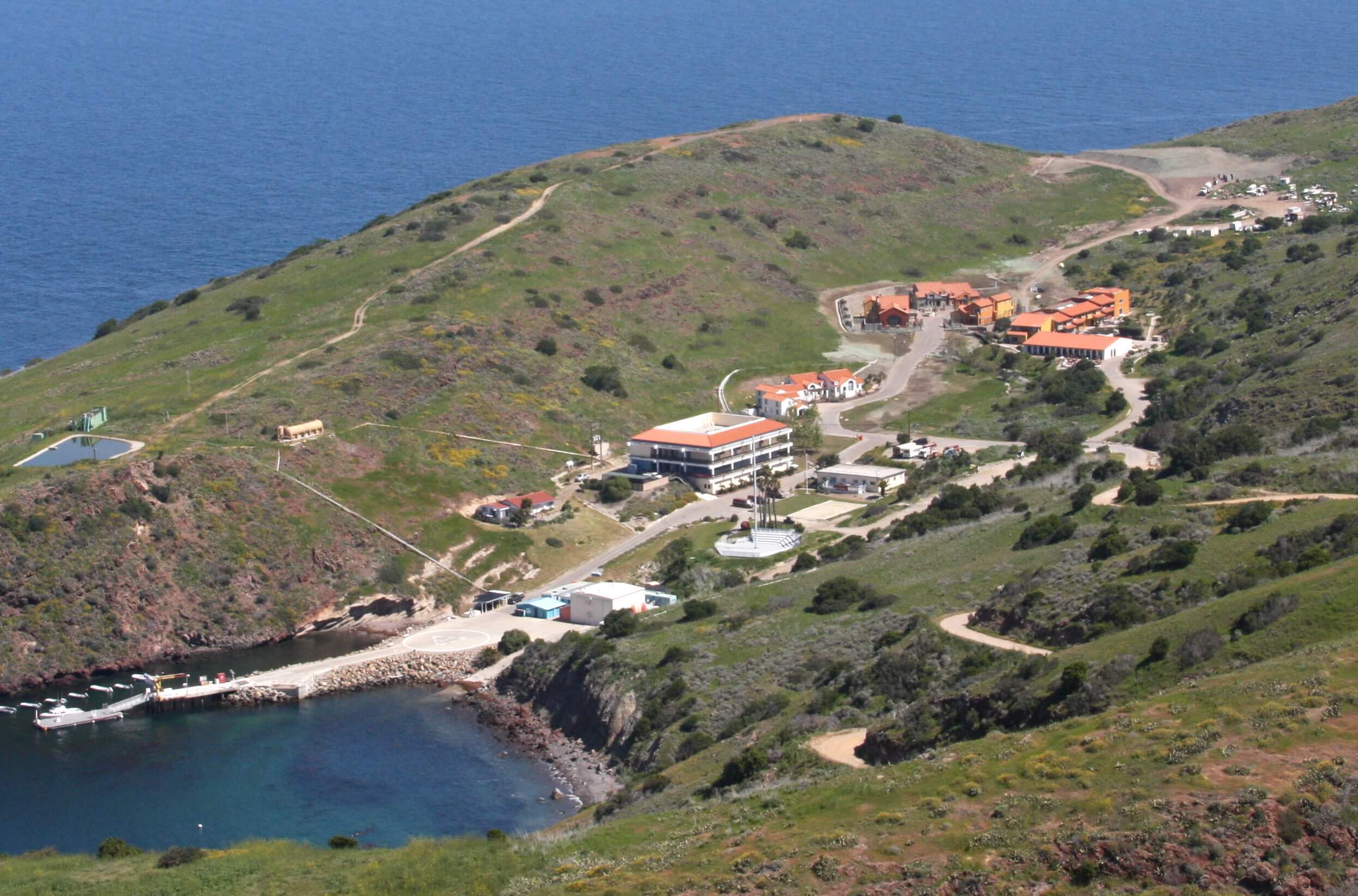 a drone photo of the Wrigley Marine Science Center, showing a group of red and white buildings along a short road leading down to a cove and boat dock