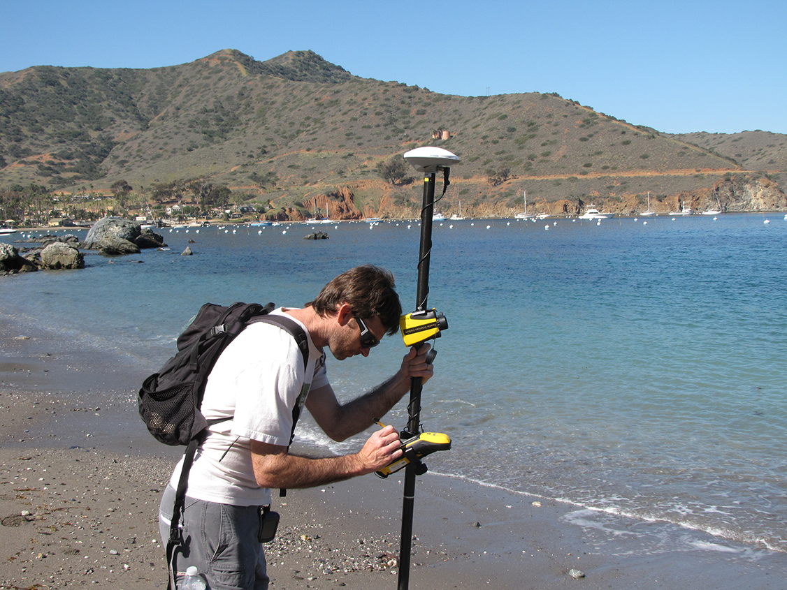 a graduate student uses surveying equipment to gather data on a Catalina Island beach