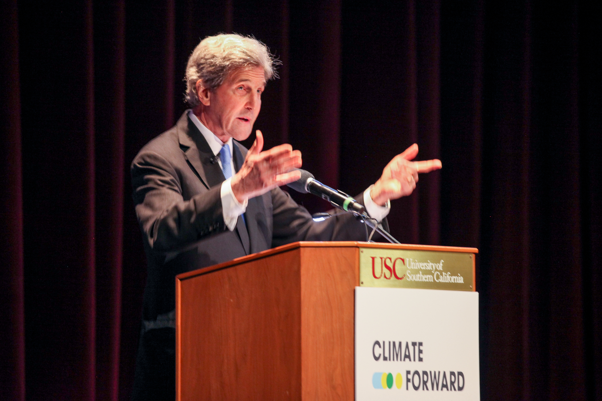 John Kerry speaking from a podium at the Climate Forward conference.