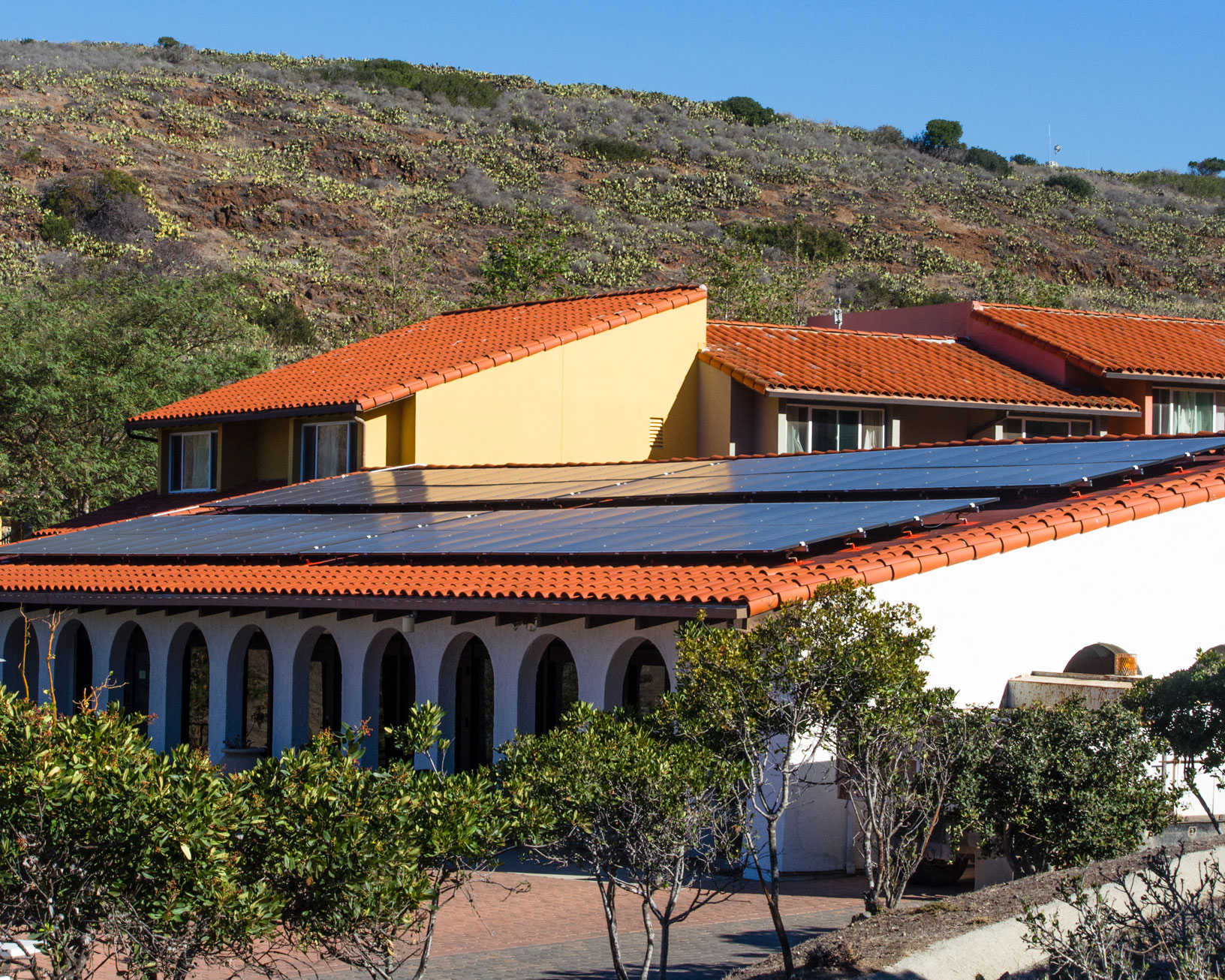 closeup view of solar panels on the roof of the Wrigley Marine Science Center dining hall with housing and a hillside in the background