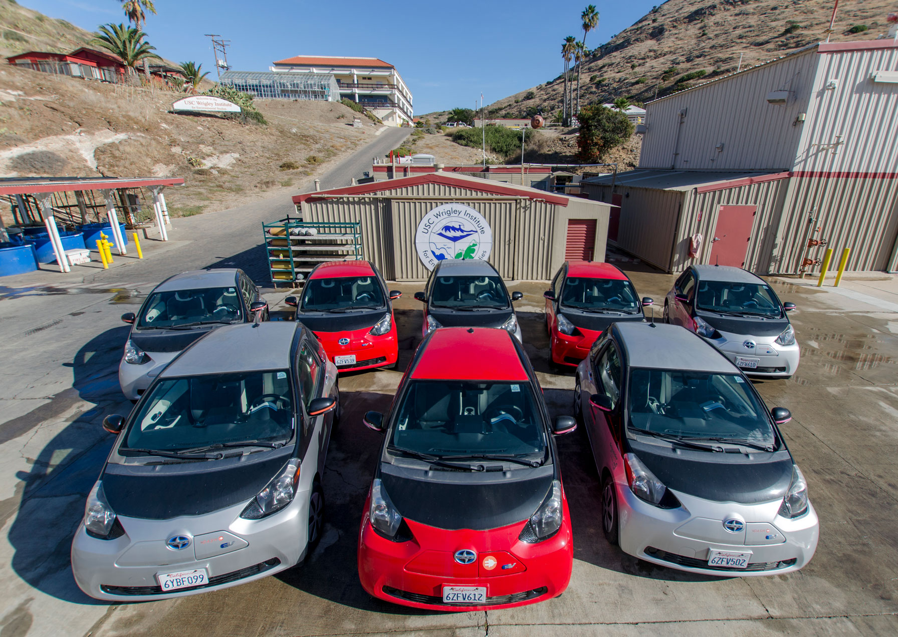 two rows of red and silver electric cars parked on a concrete helipad