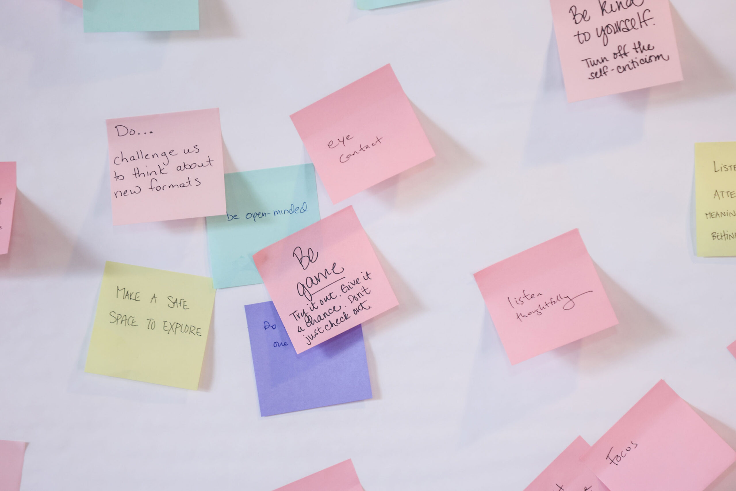 closeup of sticky notes, attached to a white board, with messages such as "listen thoughfully" and "be kind to yourself"