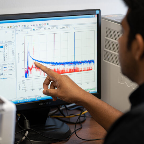 student pointing to red and blue graphs on a computer