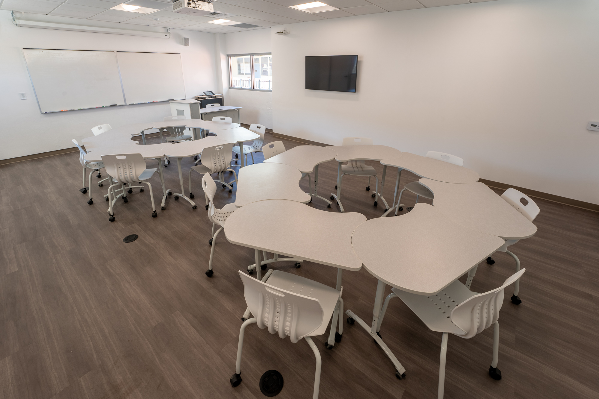 a classroom with white board, gray flooring, and modular chairs and tables organized into circular configurations