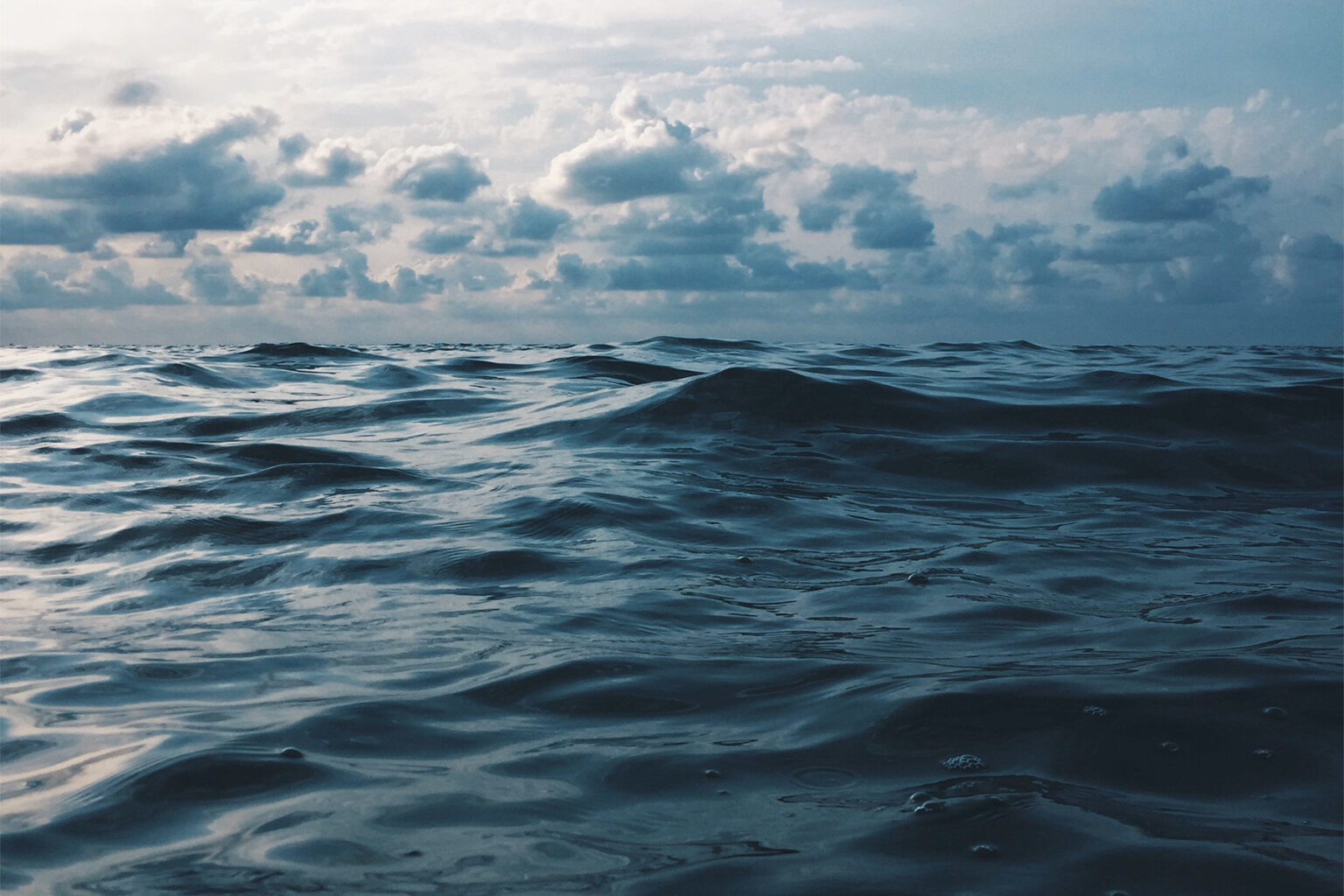 dark blue ocean waves ripple under a cloudy sky