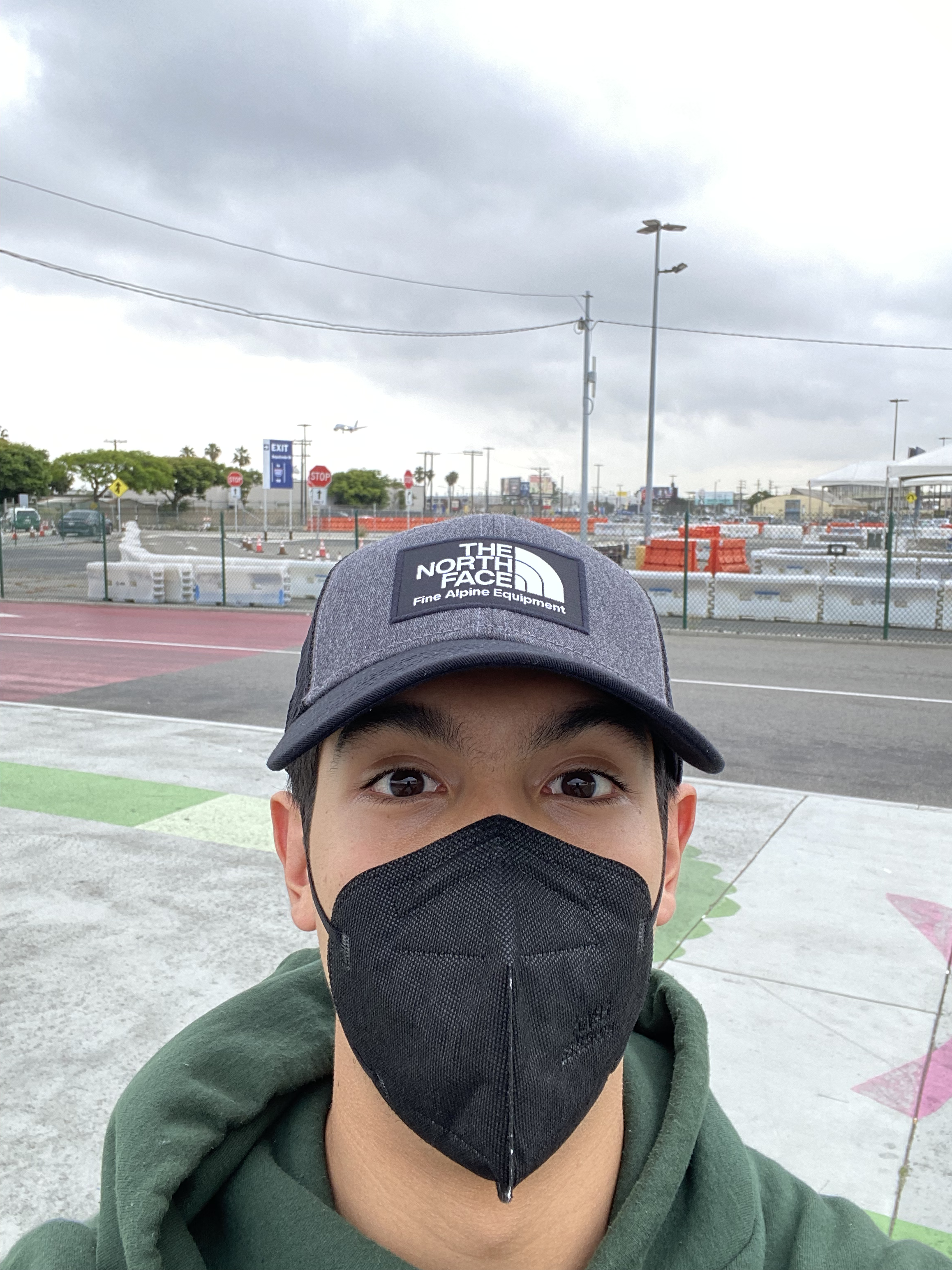 person wearing a black KN95 mask and a baseball cap takes a selfie