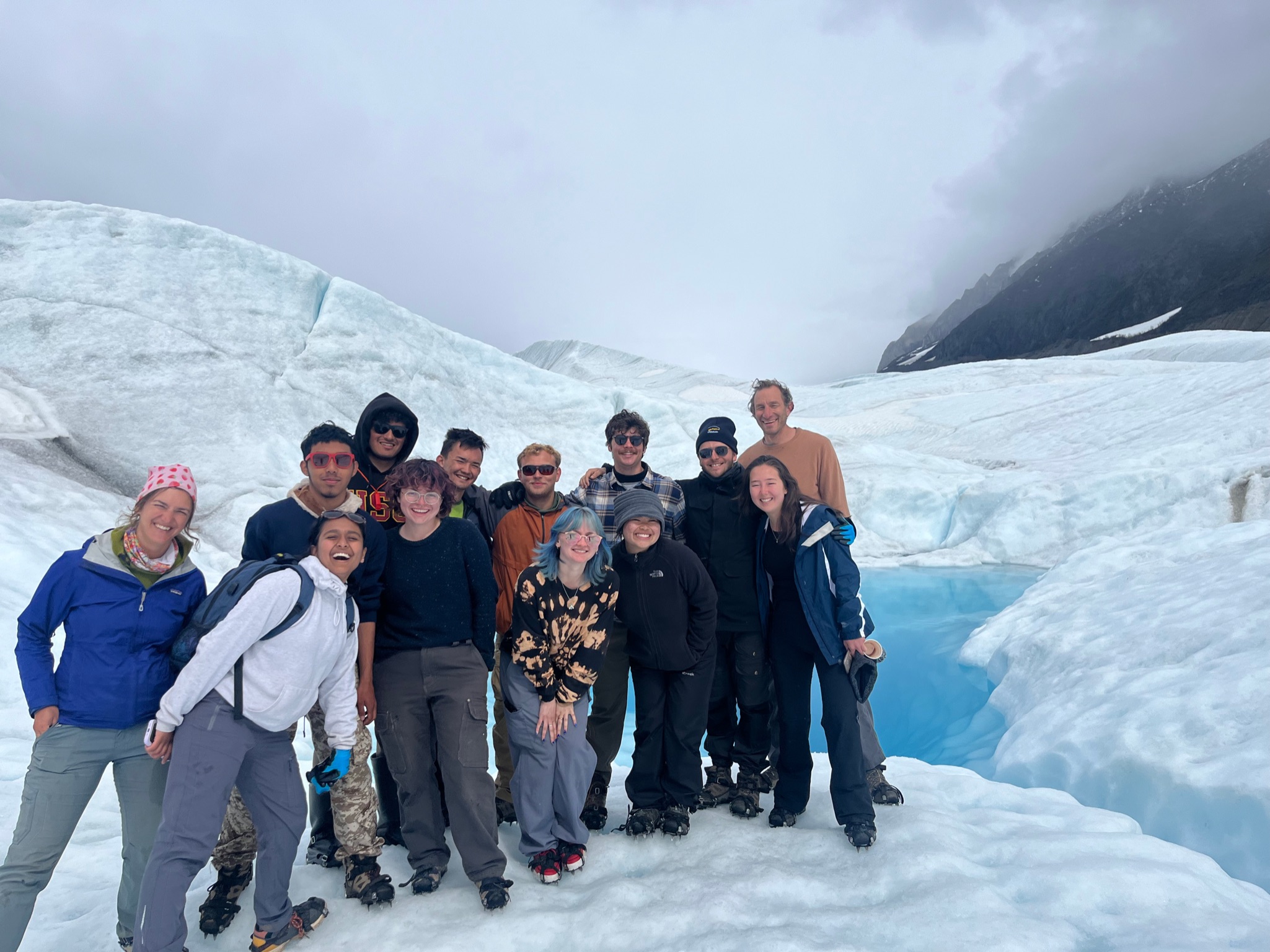 group of people stand front of a glacier in Alaska