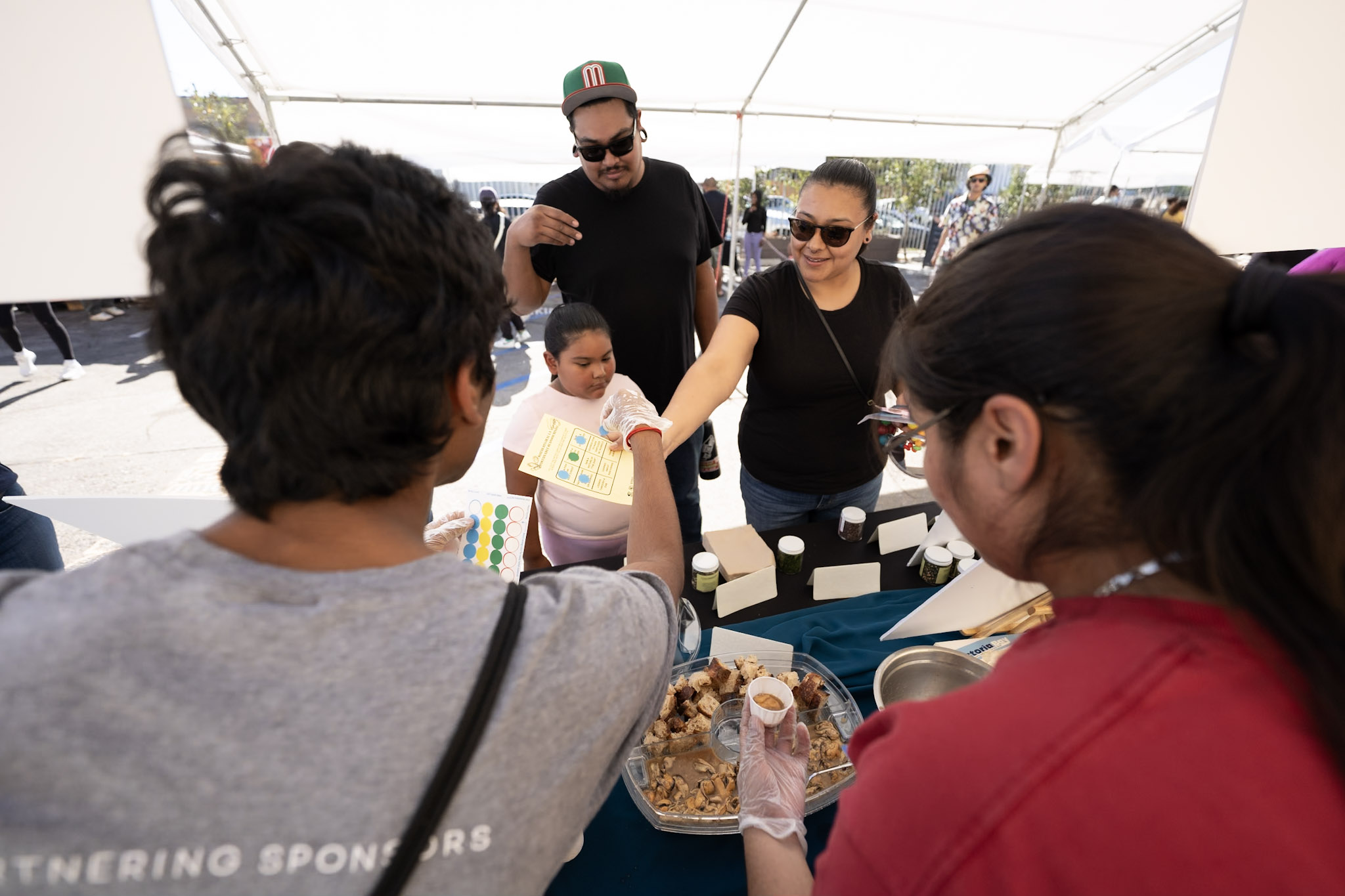 two adults and a child stand on front of a tasting table manned by volunteered