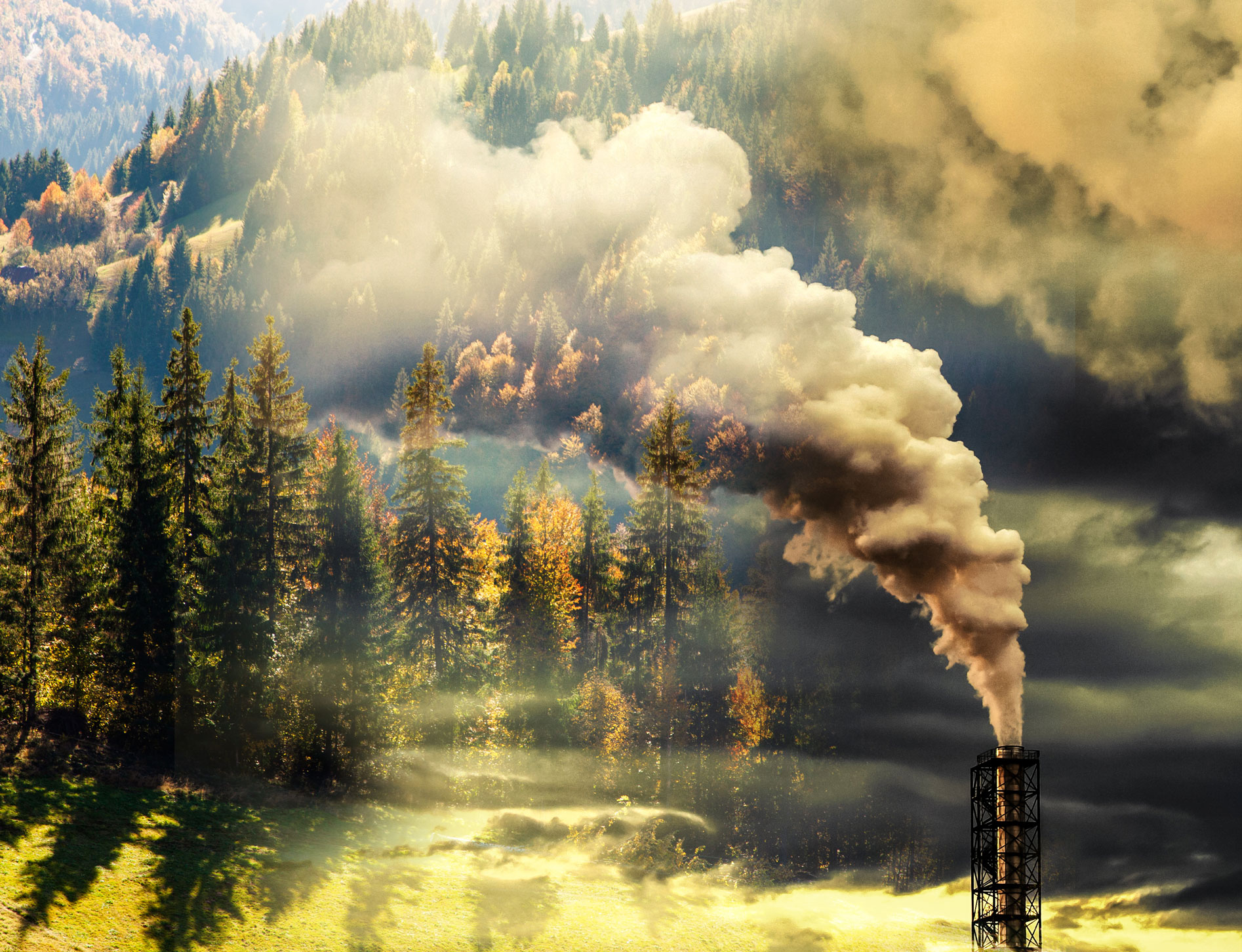 a power plant chimney pumps out polluting smoke in front of a forested mountainside